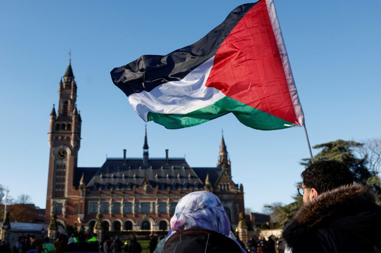 Protesters hold a Palestinian flag as they gather outside the International Court of Justice (ICJ).