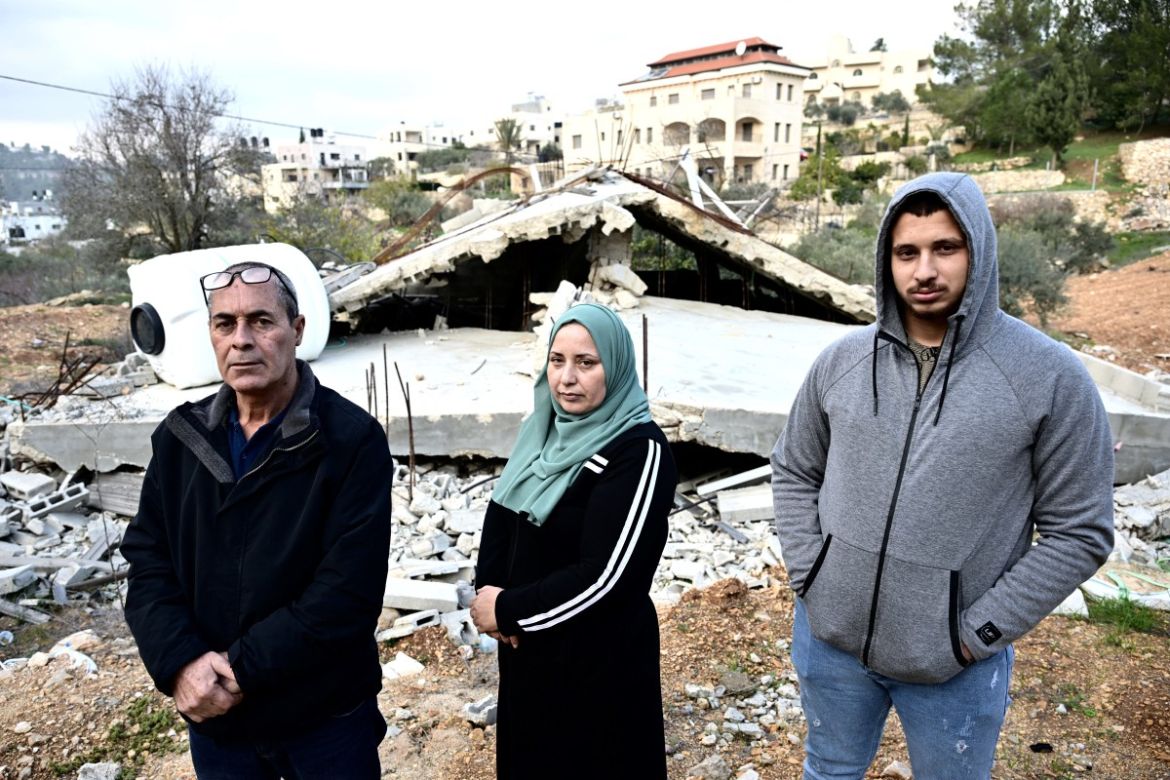 Palestinian family (LtoR) Waji, Ghadeer and Luai al-Atrash pose in front of their bulldozed home in Al-Walaja