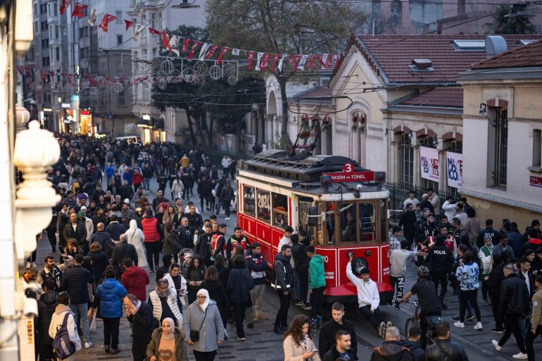 Pessoas passam por um bonde histórico na rua Istiklal durante os preparativos para celebrar o Ano Novo de 2024 em Istambul, em 31 de dezembro de 2023. (Foto de YASIN AKGUL / AFP)