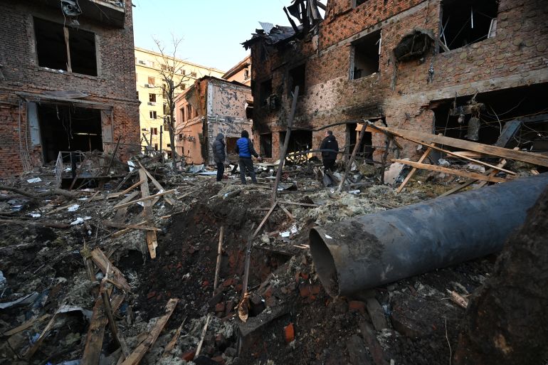 Dărâmături împrăștie străzile din Harkov după ce o dronă rusă a lovit un bloc de apartamente. Locuitorii inspectează pagubele.