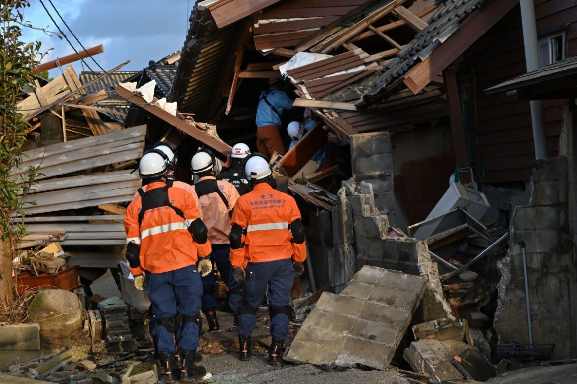 Firefighters inspect collapsed wooden houses in Wajima, Ishikawa prefecture.