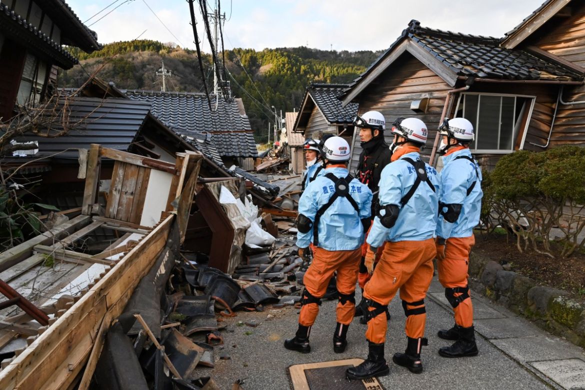 Firefighters inspect collapsed wooden houses in Wajima, Ishikawa prefecture.