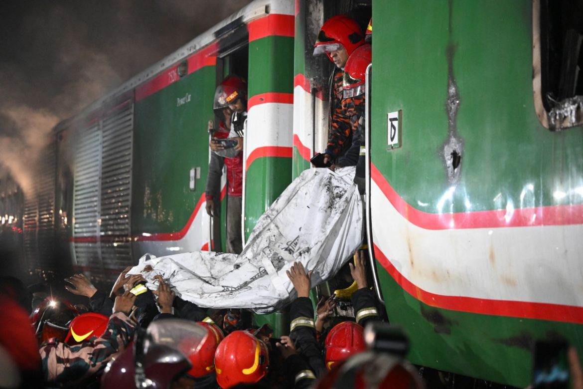 Rescue personnel remove the remains of body from a burnt out carriage of the Benapole Express in Dhaka on January 5, 2024. - Five people were killed in Bangladesh after a passenger train which was arriving in the capital Dhaka from the western city of Jessore, caught fire on January 5, 2024, with police suspecting an arson attack during unrest ahead of national elections boycotted by the opposition.