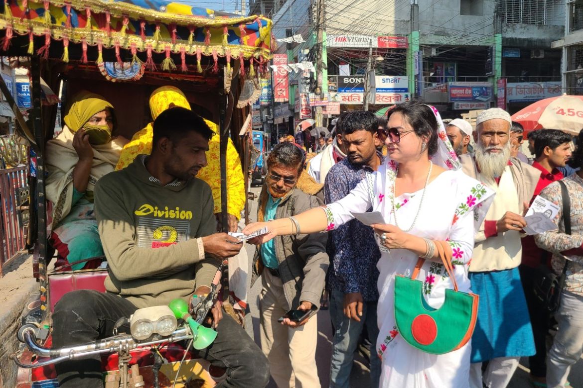 In this photograph taken on January 4, 2024, transgender candidate Anwara Islam Rani gives a leaflet to a rickshaw puller during a campaign event in Rangpur, ahead of Bangladesh's general election on January 7.