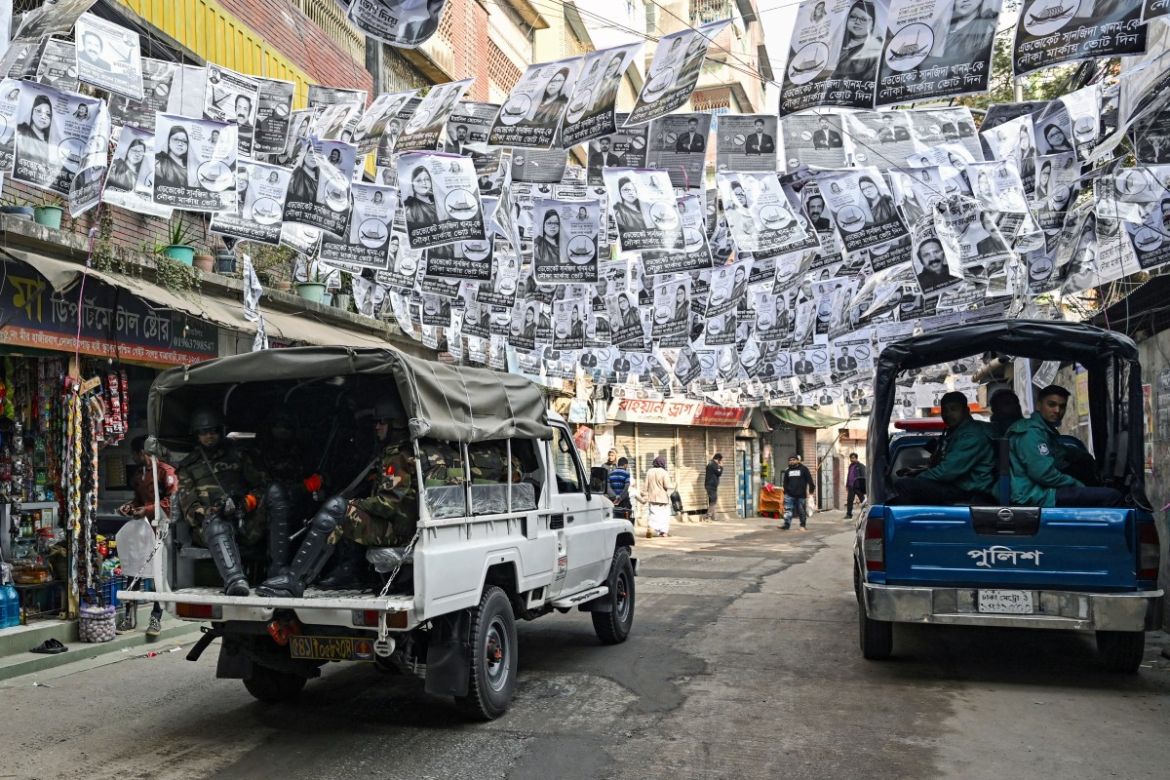 Security personnel patrol a street lined with election posters on the eve of Bangladesh's general elections in Dhaka on January 6, 2024.
