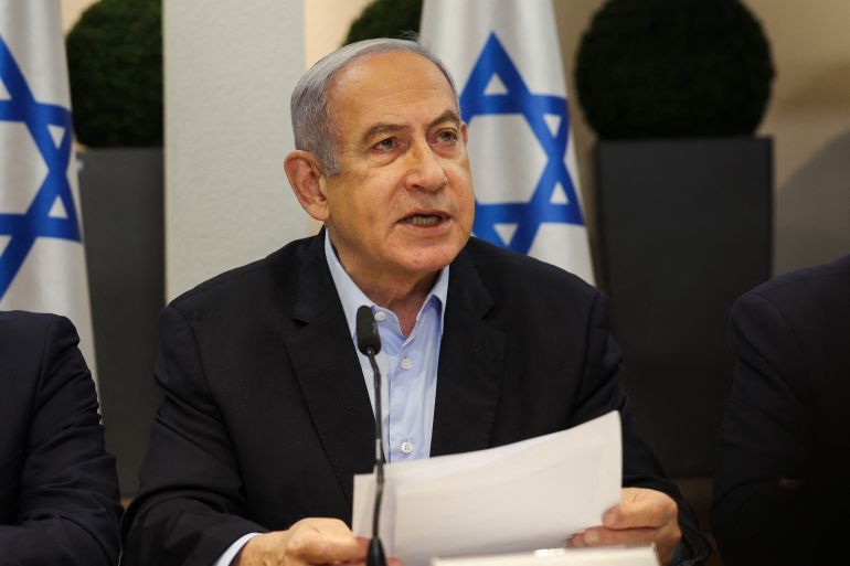 un uomo in giacca e cravatta parla davanti a una bandiera israeliana