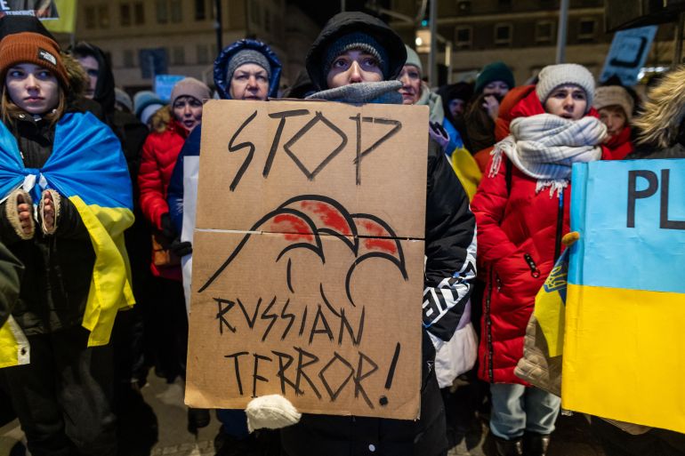 Protesters in Poland calling for tougher sanctions on Russia. One is holding a large placard with a picture of a bloodied claw and the words 'Stop Russian Terror!'