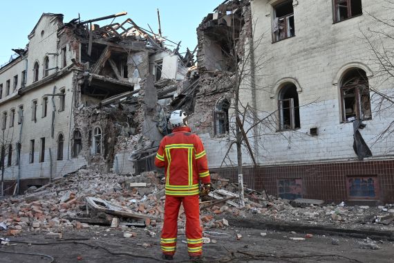 Ukraynalı bir kurtarıcı, Kharkiv'deki füze saldırısı sonucu kısmen yıkılan bir konut binasının yanında duruyor