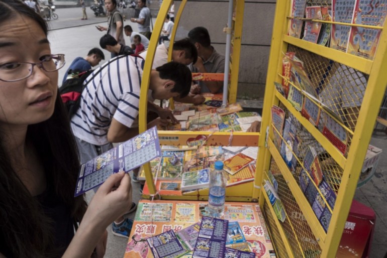 epa03826522 Residentes locais compram raspadinhas em uma loja da Loteria de Bem-Estar da China, perto de uma estação rodoviária em Pequim, China, em 16 de agosto de 2013. A loteria estatal tem pontos de venda que atendem a 95% da população e, em 2012, atingiu 151,03 bilhões de RMB (20 bilhões de euros). ) em vendas desde sua estreia em 1987. Além de empregar mais de 75.000 funcionários, a loteria financia uma ampla gama de programas de bem-estar social e instituições de caridade.  EPA/ADRIAN BRADSHAW