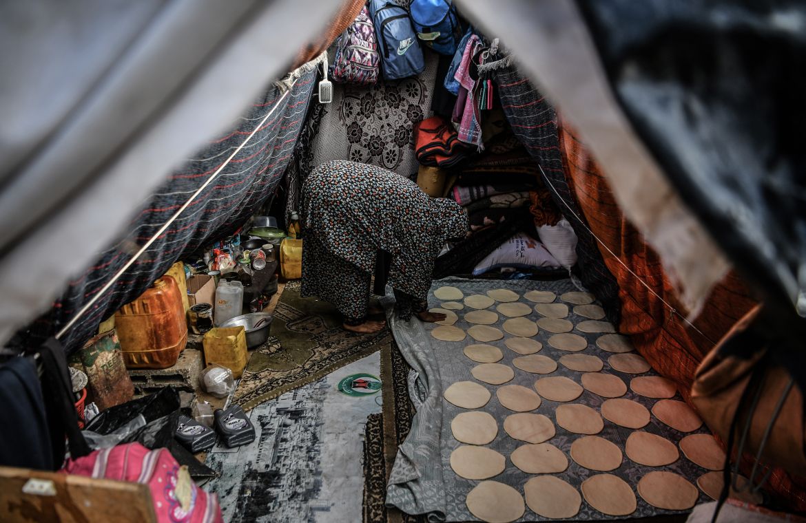 A woman prepares bread in a makeshift tent where Palestinians, who left their homes to protect themselves from Israeli bombardment, stay during the cold weather as they struggle with hard living conditions in Rafah