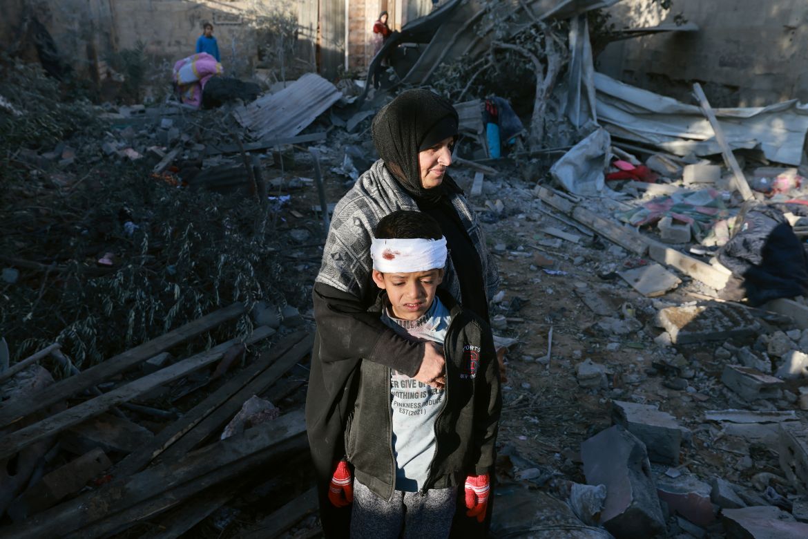 A Palestinian woman embraces a lightly injured boy as they check the rubble of a building following Israeli bombardment, on January 18, 2024 in Rafah