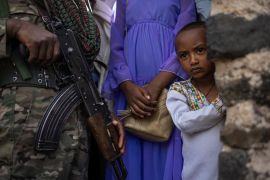 A member of the Amhara police force stands guard next to Ethiopian Orthodox worshippers at the Fasilides Bath