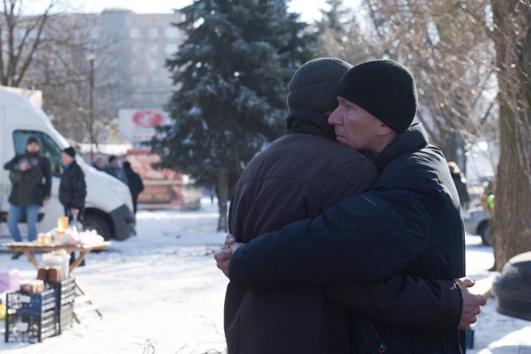 Two men embrace each other at the site of a missile strike in Donetsk on January 21