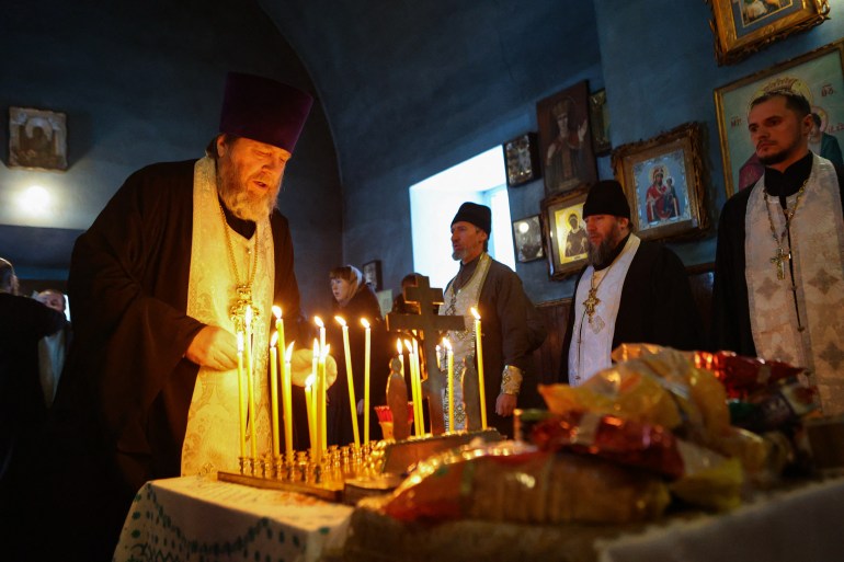 A Russian Orthodox priest lighting candles at a service for those killed in the Belgorod plane crash 