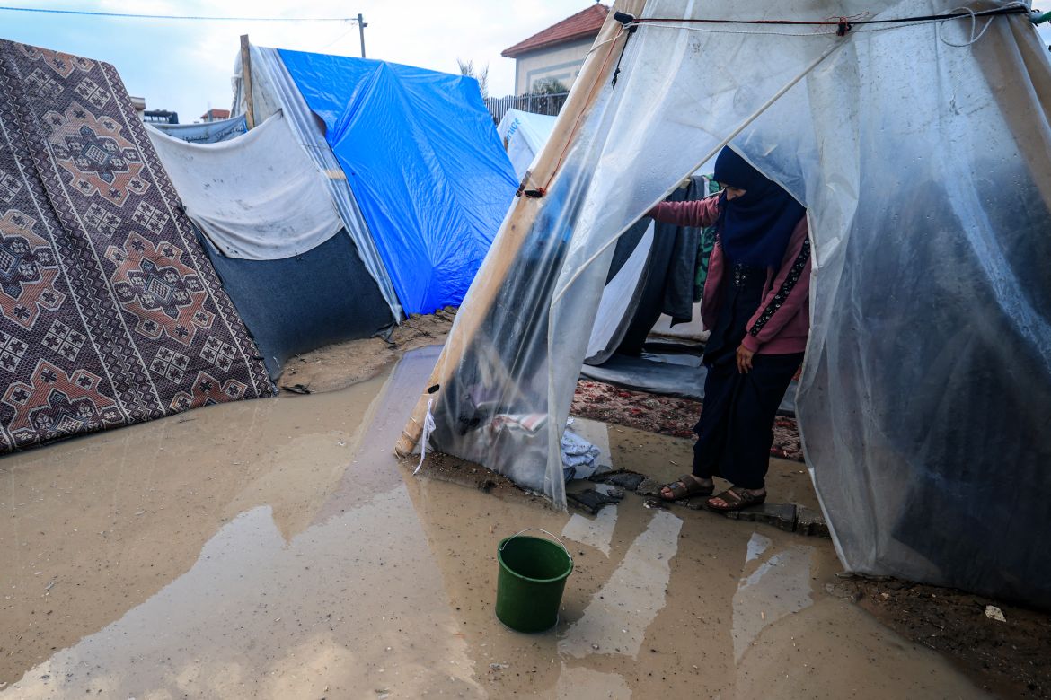A displaced Palestinian woman stands at the entrance of a tent flooded by heavy rain, at a makeshift camp set up by people who fled the ongoing battles between Israel and Hamas militants, in Rafah