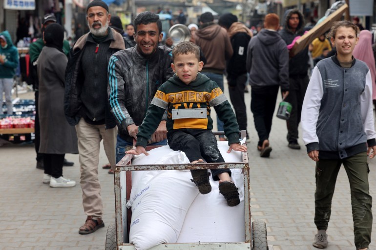 a child sits on white bags and is pushed by an adult