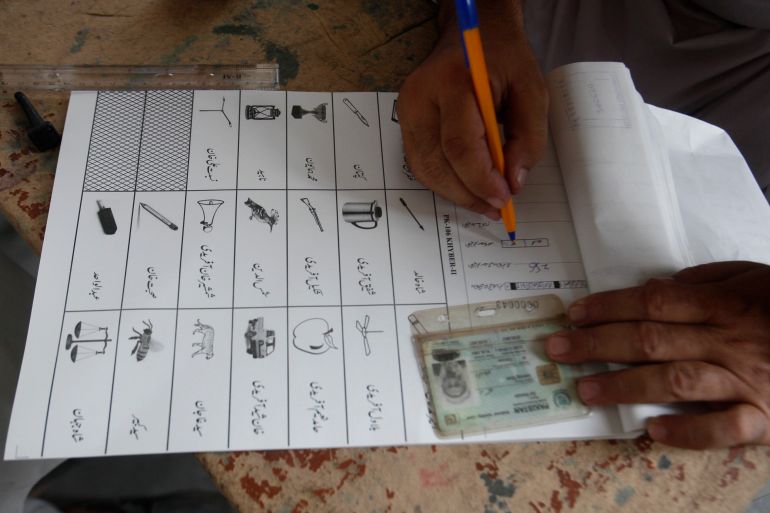 An election worker prepares ballot paper for a tribesman, waiting to cast his vote in a polling station during an election for provincial seats in Jamrud, a town of Khyber district, Pakistan in 2019.