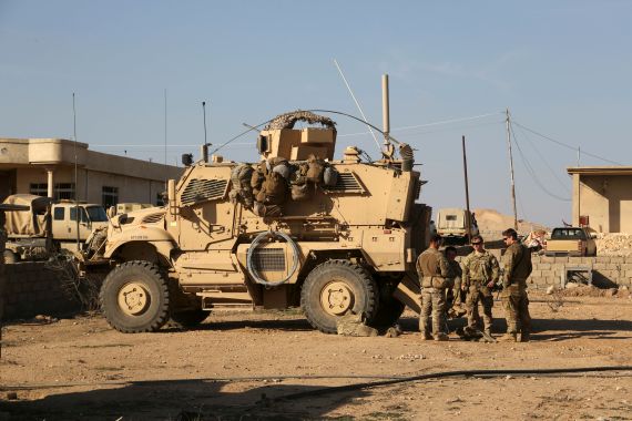 U.S. Army soldiers stand outside their armored vehicle on a joint base with Iraqi army south of Mosul, Iraq.