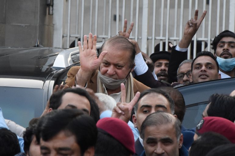 Pakistan's former Prime Minister Nawaz Sharif, center in brown coat, waves to his supporters as he leaves after a court hearing in Islamabad, Pakistan, Tuesday, Dec. 12, 2023. A Pakistani court on Tuesday overturned the 2018 conviction of former Prime Minister Sharif in a graft case and acquitted him, clearing his path to run in the parliamentary elections set to be held in February. (AP Photo/W.K. Yousufzai)