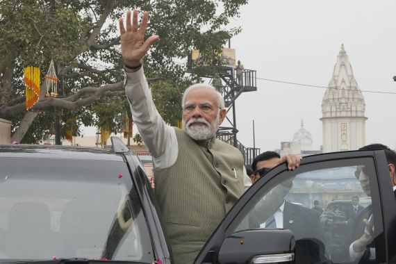 Indian Prime Minister Narendra Modi waves to the crowd during a road show before inaugurating a new airport and a railway station in Ayodhya, India.
