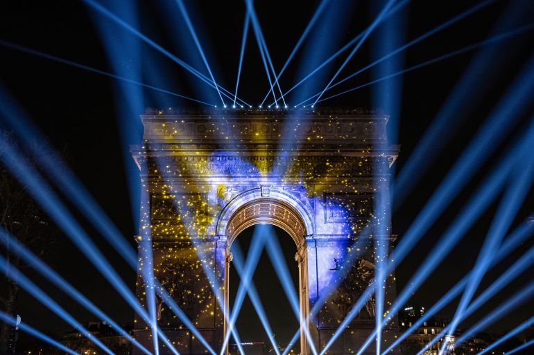 The Arc de Triomphe illuminated in blue and gold during a New Year's Eve light show