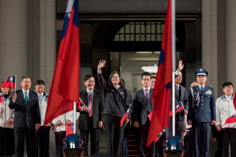 Tsai Ing-wen başkanlık ofisinin merdivenlerinde el sallıyor.  İki Tayvan bayrağı arasında duruyor. 
