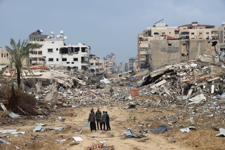 Palestinians walk past the building destroyed in the Israeli bombardment of the Gaza Strip in Gaza City on January 3
