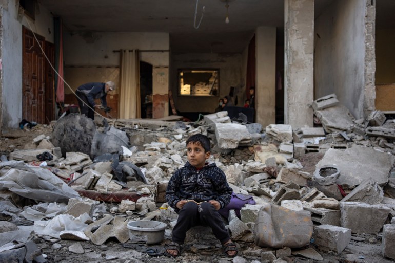 A small boy sits on a pile of rubble following an airstrike