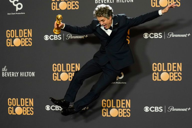 Mark Ruffalo jumping in the air in front of 81st Golden Globes flex