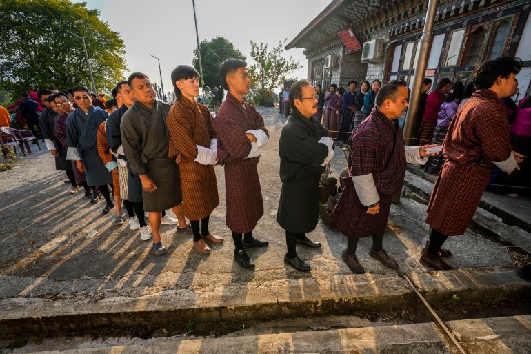 Bhutanese people in traditional attire queue up to cast their votes in the national elections in Deothang