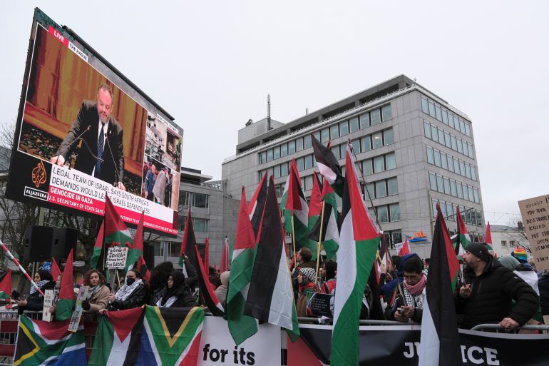 Protesters carry flags and banners outside the International Court of Justice in The Hague, Netherlands, Friday, Jan. 12, 2024. The United Nations' top court opened hearings Thursday into South Africa's allegation that Israel's war with Hamas amounts to genocide against Palestinians, a claim that Israel strongly denies. (AP Photo/Patrick Post)