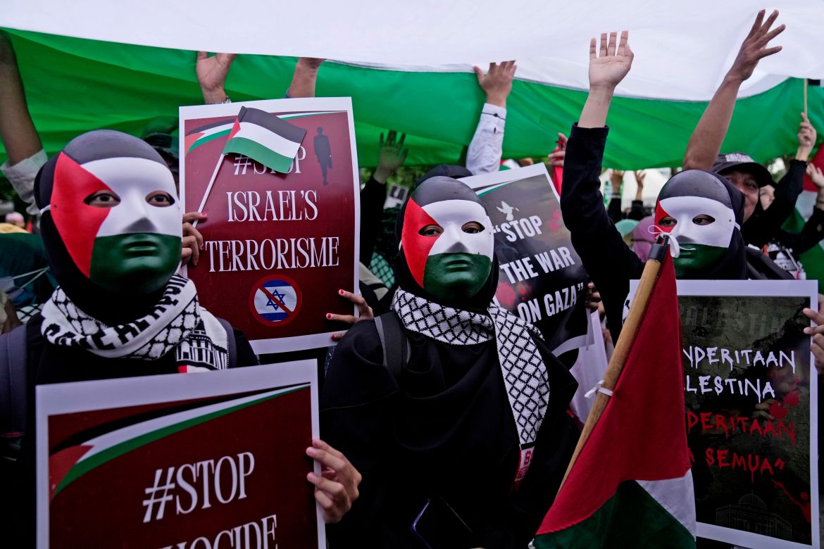 Protesters wearing masks with the colors of Palestinian flag hold posters during a rally in support of the Palestinians outside the U.S. Embassy in Jakarta, Indonesia, Saturday, Jan. 13