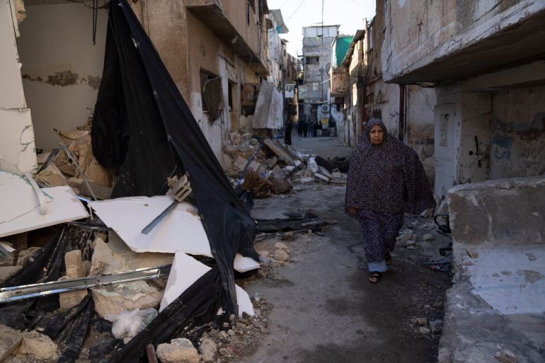 A Palestinian refugee walks past a destroyed houses in the West Bank refugee camp of Tulkarem, Friday