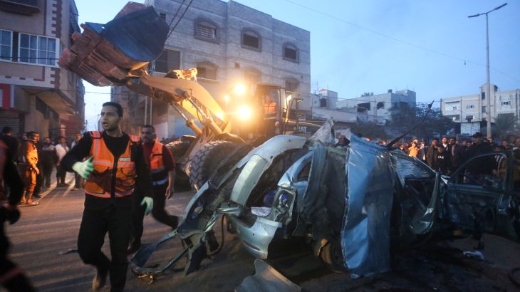 Palestinians surround a car hit by an Israeli air raid in Rafah, Gaza Strip