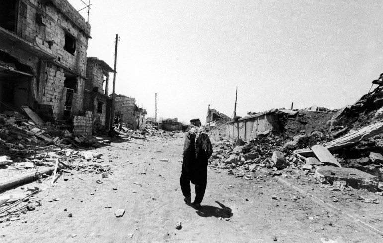 An elderly Palestinian refugee wanders through the town of Sabra, in West Beirut, on Aug. 2, 1982, amid extensive destruction caused by 14 hours of lane, seana d artillery bombardment by the Israeli forces the day before. (AP Photo/Dear)