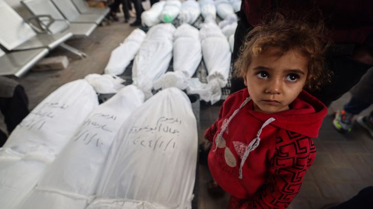 A child stands near the bodies of family members of the Nofal family, after they were killed during Israeli bombardment, on January 10, 2024 at al-Najar hospital in Rafah in the Gaza Strip. (Photo by AFP) /