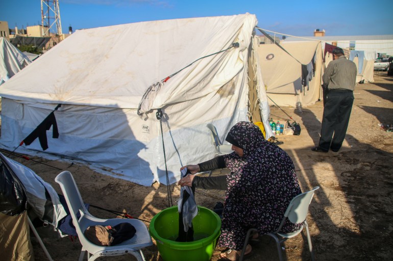 A Palestinian woman does laundry outside a refugee tent along the Gaza Strip