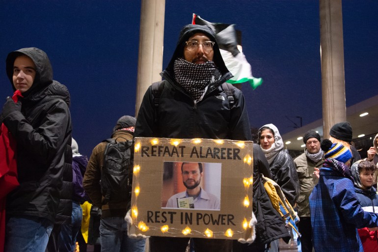 Man protesting with sign that has Alareer's photo on it