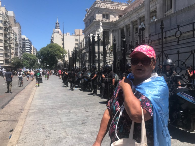 Nancy Pereyra, a retiree wearing a pink ballcap and an Argentine flag wrapped around her shoulders on the streets of Buenos Aires.