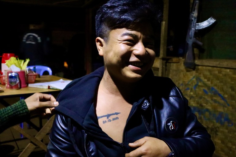   Demoso PDF-Kämpfer zeigt ein Tattoo zur Erinnerung an das Datum, an dem er durch ein militärisches Rollenspiel verletzt wurde.  Er grinste und zog seine Jacke zurück, um das Tattoo zu zeigen.