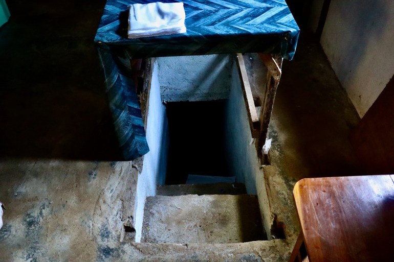 The entrance to a bomb shelter in a clandestine hospital in Kayah. It's beneath a table. with steep steep narrow steps leading underground.