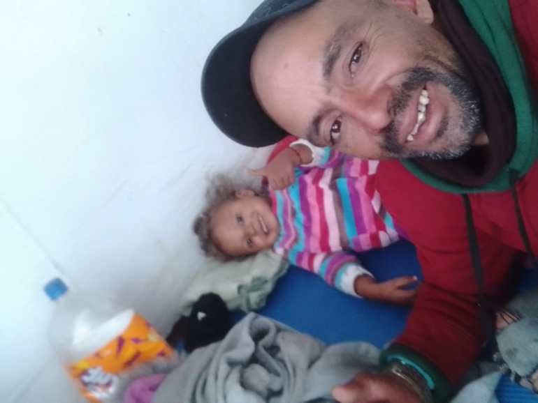 Victor Hidalgo Lopez, usando um boné de beisebol, posa para uma selfie com sua filha pequena.
