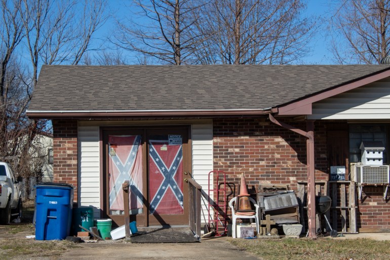 A confederate flag is displayed outside a single-storey red brick house.