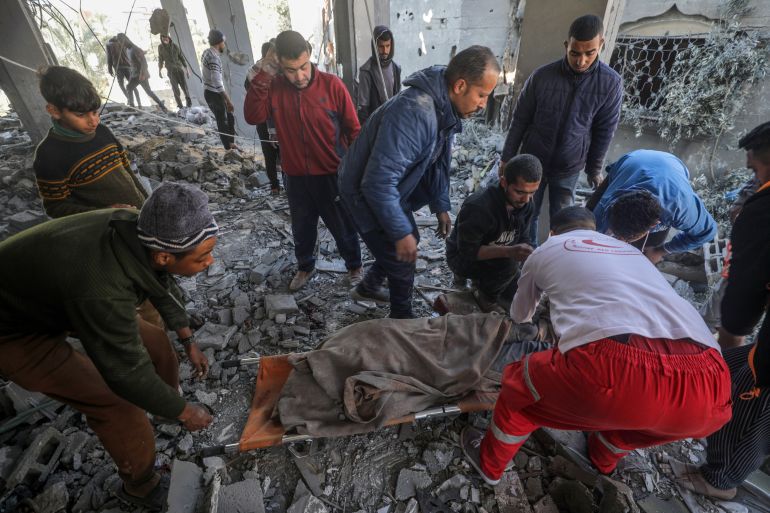 Palestinians recover a body from the rubble of a destroyed house following Israeli air strikes, in Deir Al Balah