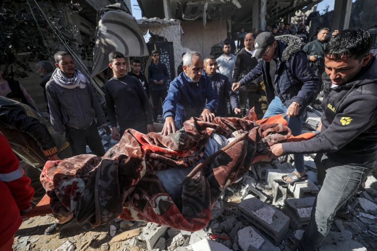 Palestinians recover a body from the rubble of a destroyed house following Israeli air strikes, in Deir Al Balah