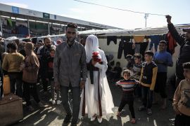 A Palestinian couple, who fled the Israeli attacks and took refuge in Durra Stadium, get married in Deir el-Balah on February 16. Relatives of the bride and groom and many other Palestinians attended the wedding near the stadium. [Abdelhakim Abu Riash/Al Jazeera]