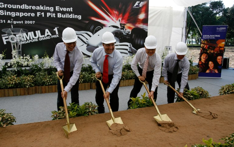 Tycoon Ong Beng Seng and Iswaran at the ground breaking ceremony for the F1 pitstop building in 2007. They are wearing hatrd hats and using a shovel.