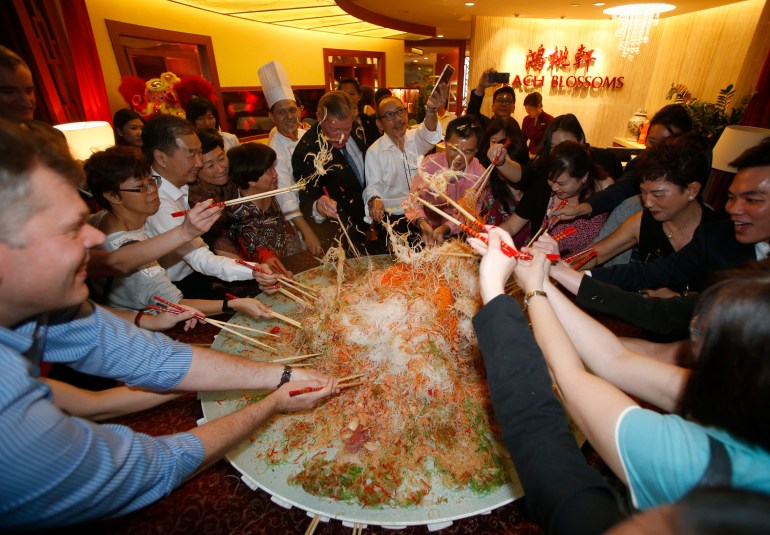 Guests toss an 88 kg plate of yusheng or raw fish during a "lo hei" dinner ahead of the Lunar New Year in Singapore January 8, 2016.