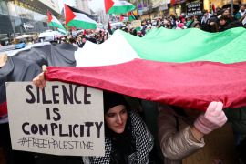 A woman holds a placard as people take part in a demonstration in support of Palestinians in Gaza, in Frankfurt, Germany [File: Kai Pfaffenbach/Reuters]