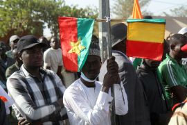 A man holds Mali and Burkina Faso flags at a rally on December 29, 2023, in Niamey, Niger, to celebrate the withdrawal of French troops. It was also attended by the prime ministers of Niger, Burkina Faso and Mali [Mahamadou Hamidou/Reuters]